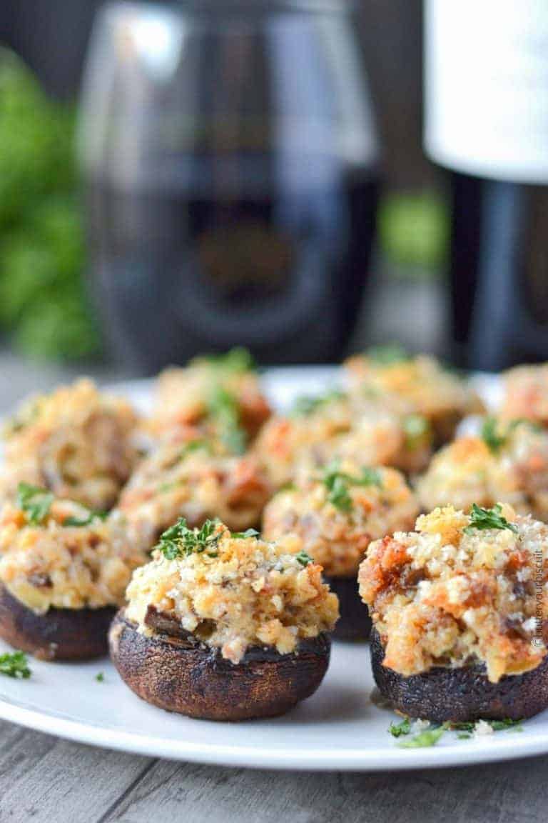 italian sausage stuffed mushrooms on a serving plate with wine