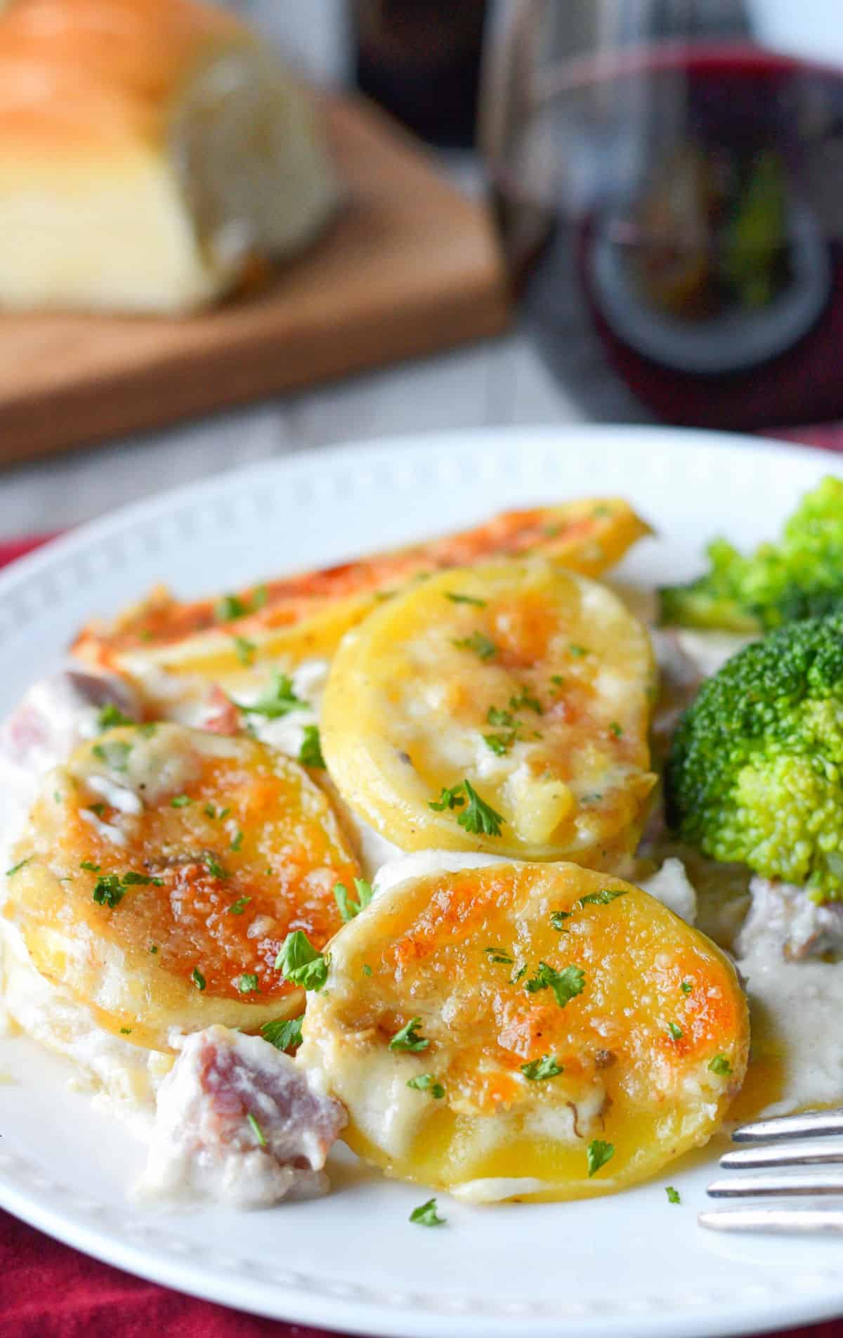 Scalloped potatoes on a plate with broccoli.