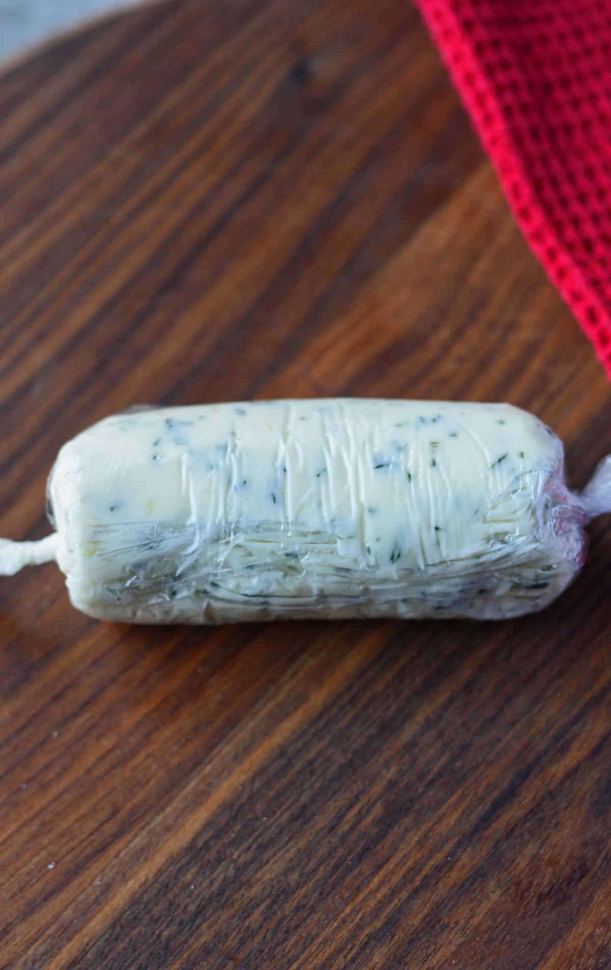 Garlic herb butter rolled up in plastic wrap.