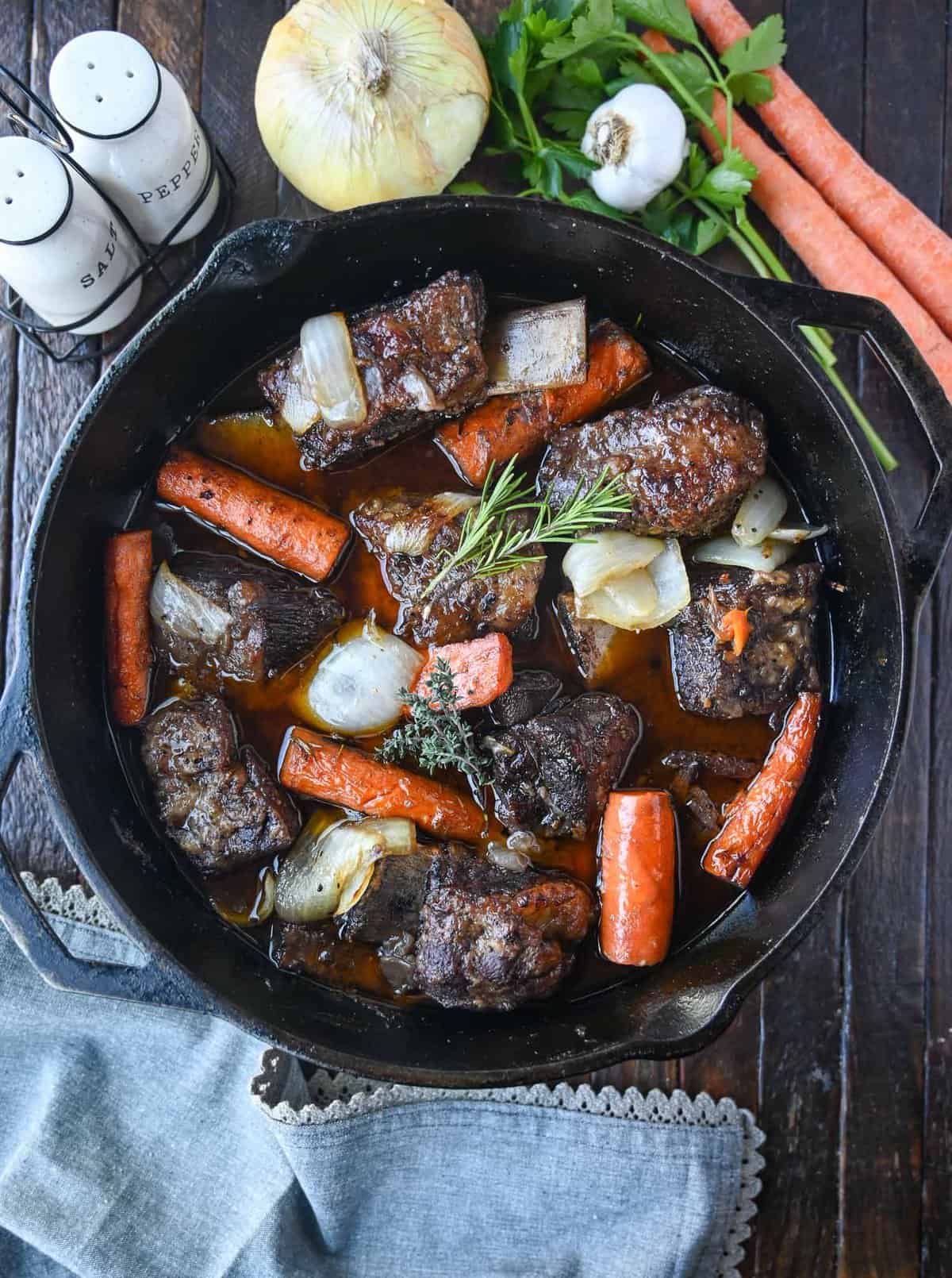 A large dutch oven with beef short ribs and carrots.