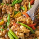 A wooden spoon scooping up some sweet and spicy chicken stir fry.