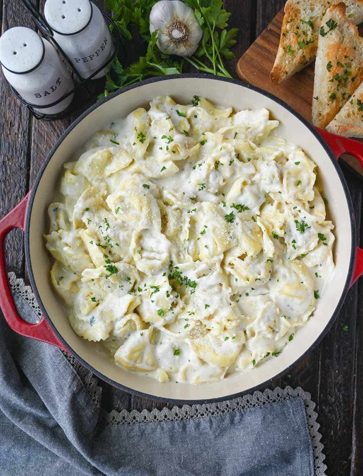 Garlic alfredo cheese tortellini in a skillet with a wooden spoon.
