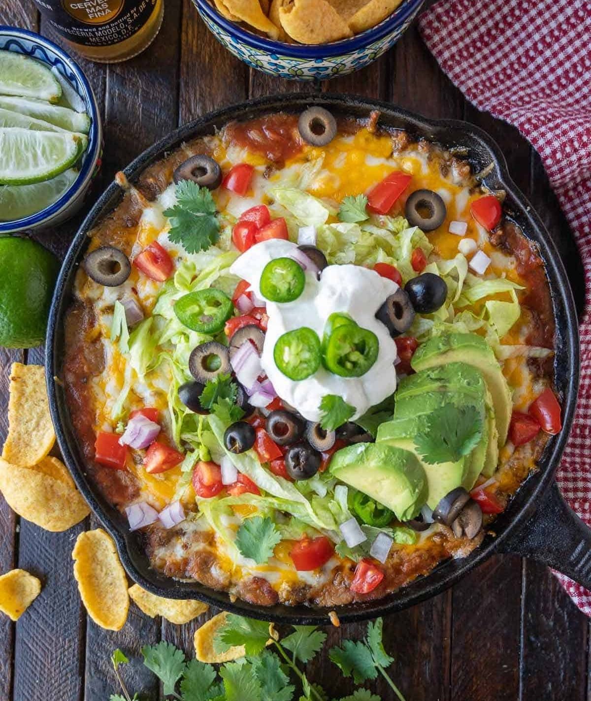 Loaded taco dip in a cast iron skillet with Fritos.