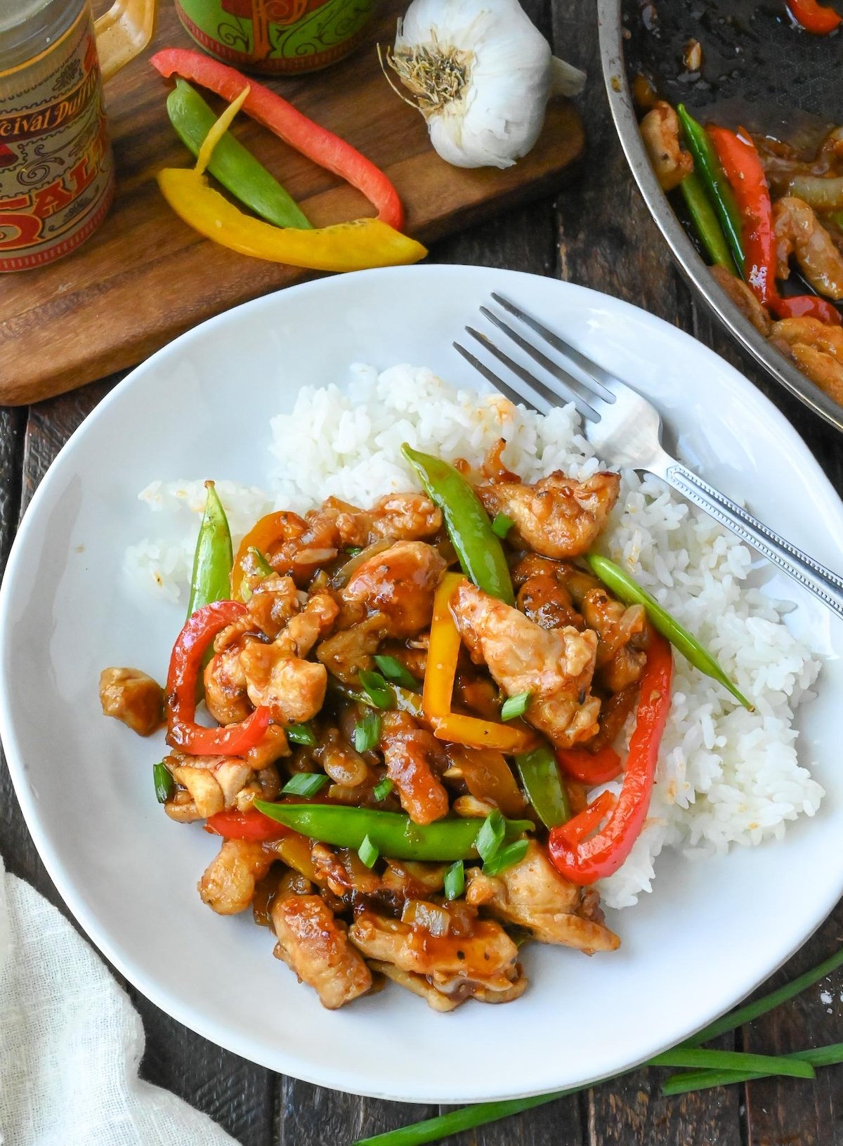 Chicken stir fry on a plate with white rice.