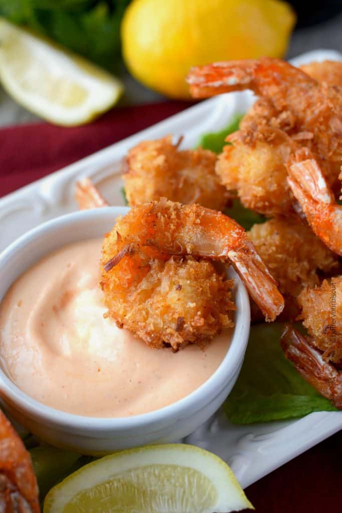 A plate of food on a table, with Shrimp and Coconut and sauce.