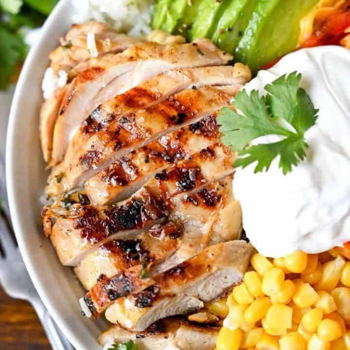 Tequila lime chicken, avacodo, cut into slices. Plus a scoop of corn and a some sour cream placed in a white bowl on top of cilantro rice.