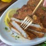 A slice of pork schnitzel being picked up with a fork.