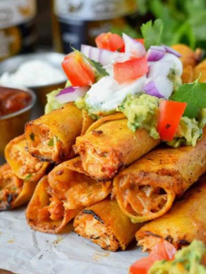 Chicken taquitos stacked with sour cream on top.