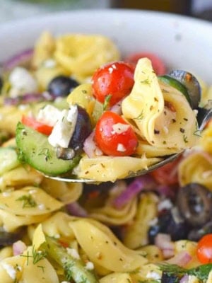A spoon scooping up some greek pasta salad.
