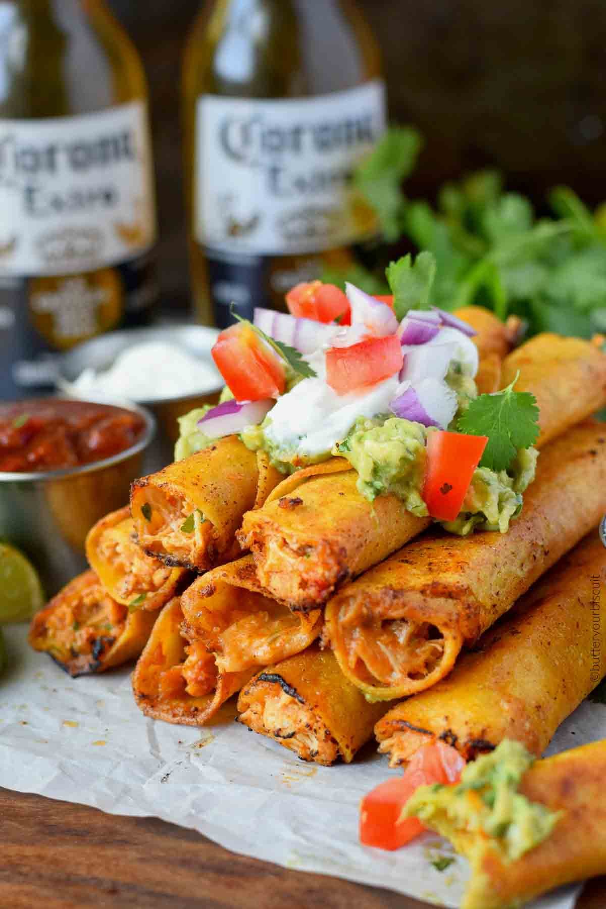 Chicken taquitos stacked up with sour cream on top.