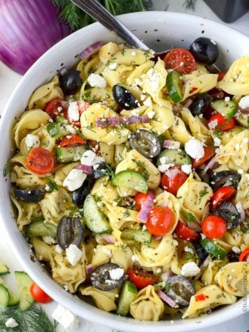 Greek tortellini pasta salad in a large white serving bowl