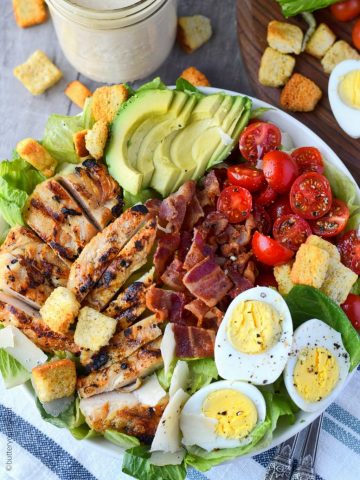 grilled chicken avocado caesar salad in a white bowl