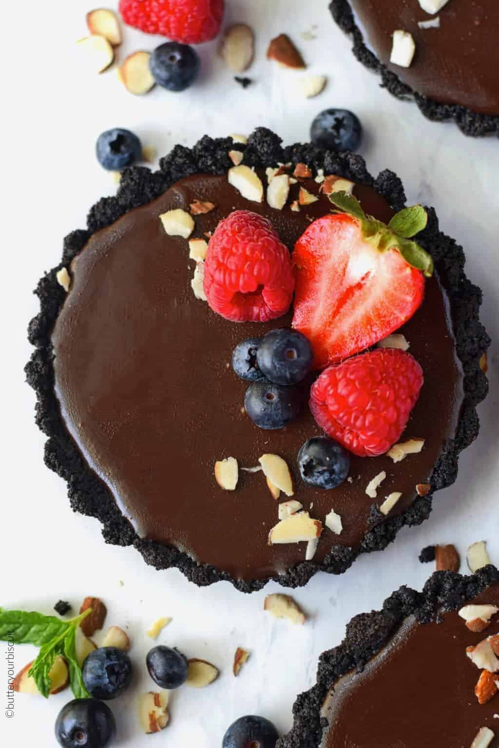 No bake chocolate mini tarts with strawberries, blueberries, rasberries and almond slivers on top