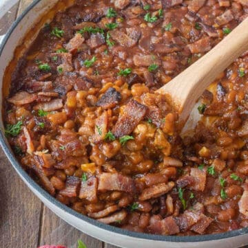 baked beans with a wooden spoon scooping some out.