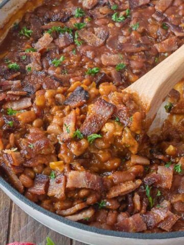 baked beans with a wooden spoon scooping some out.
