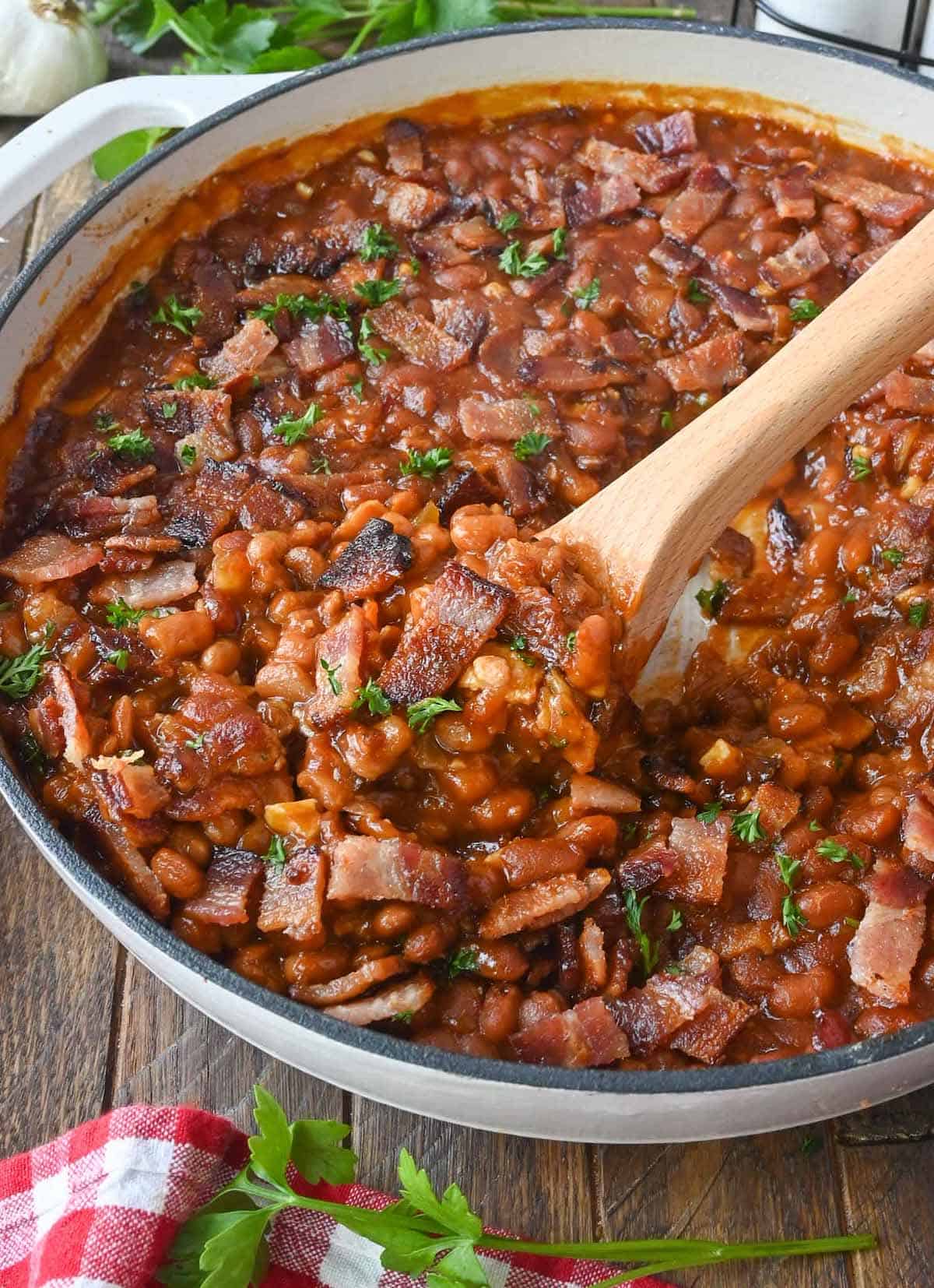 A large skillet with baked beans and a serving spoon.