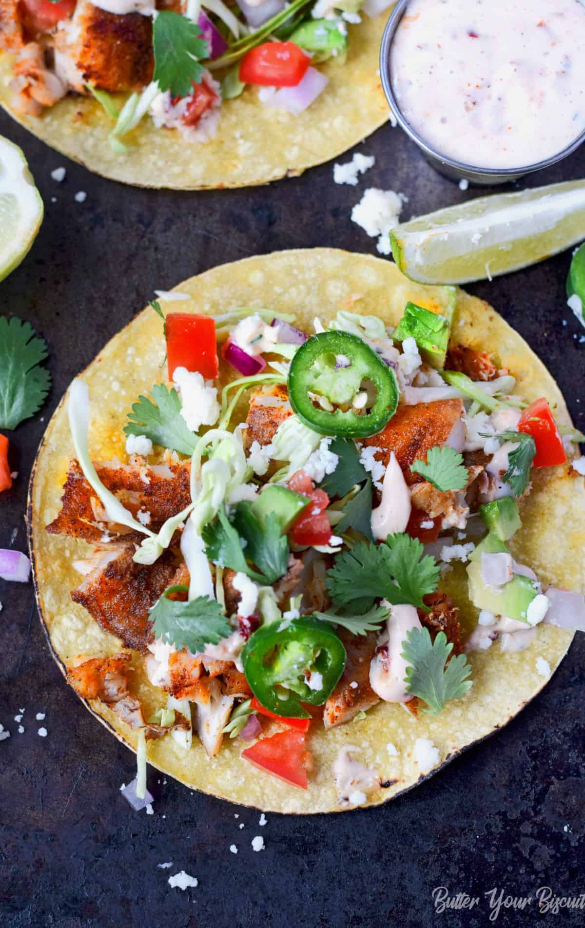 Corn tortilla with fish and condiments on top.