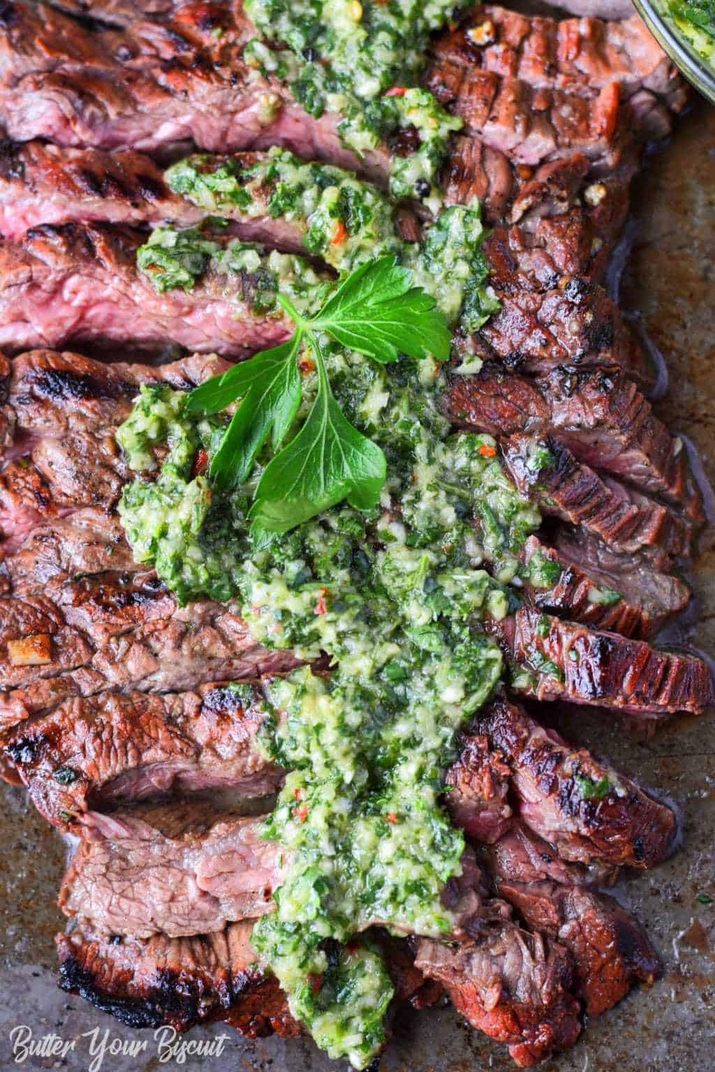 Grilled skirt steak and chimichurri sliced on a baking sheet