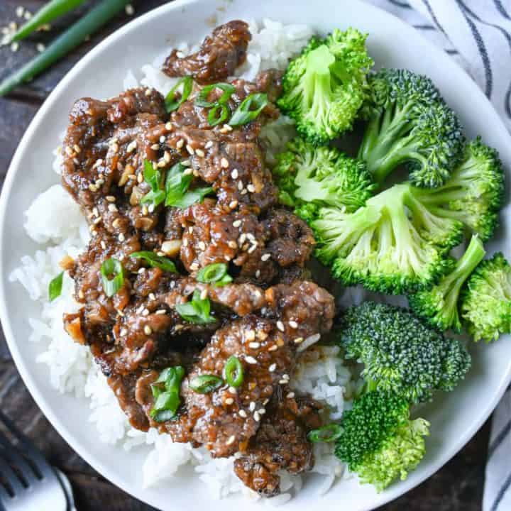 Mongolian beef on a side of white rice with steamed broccoli in a white bowl.