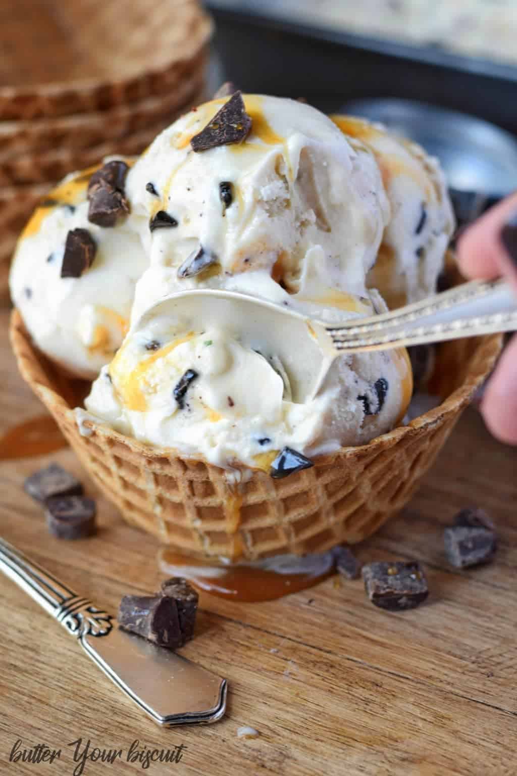 A spoon picking up a bite of ice cream in a waffle bowl.