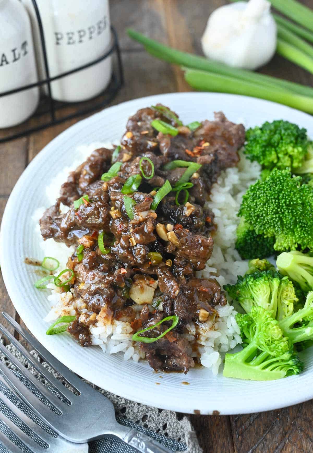 Mongolian beef on top of white rice with a side of broccoli.