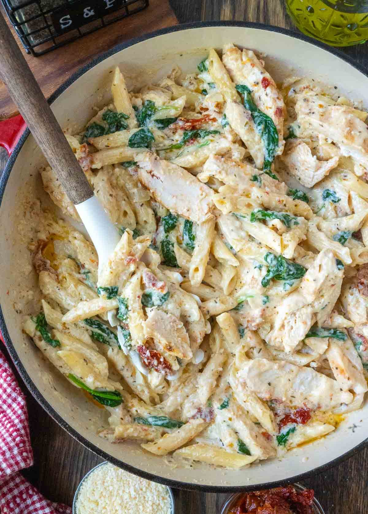 Tuscan chicken pasta in a skillet with a spoon.