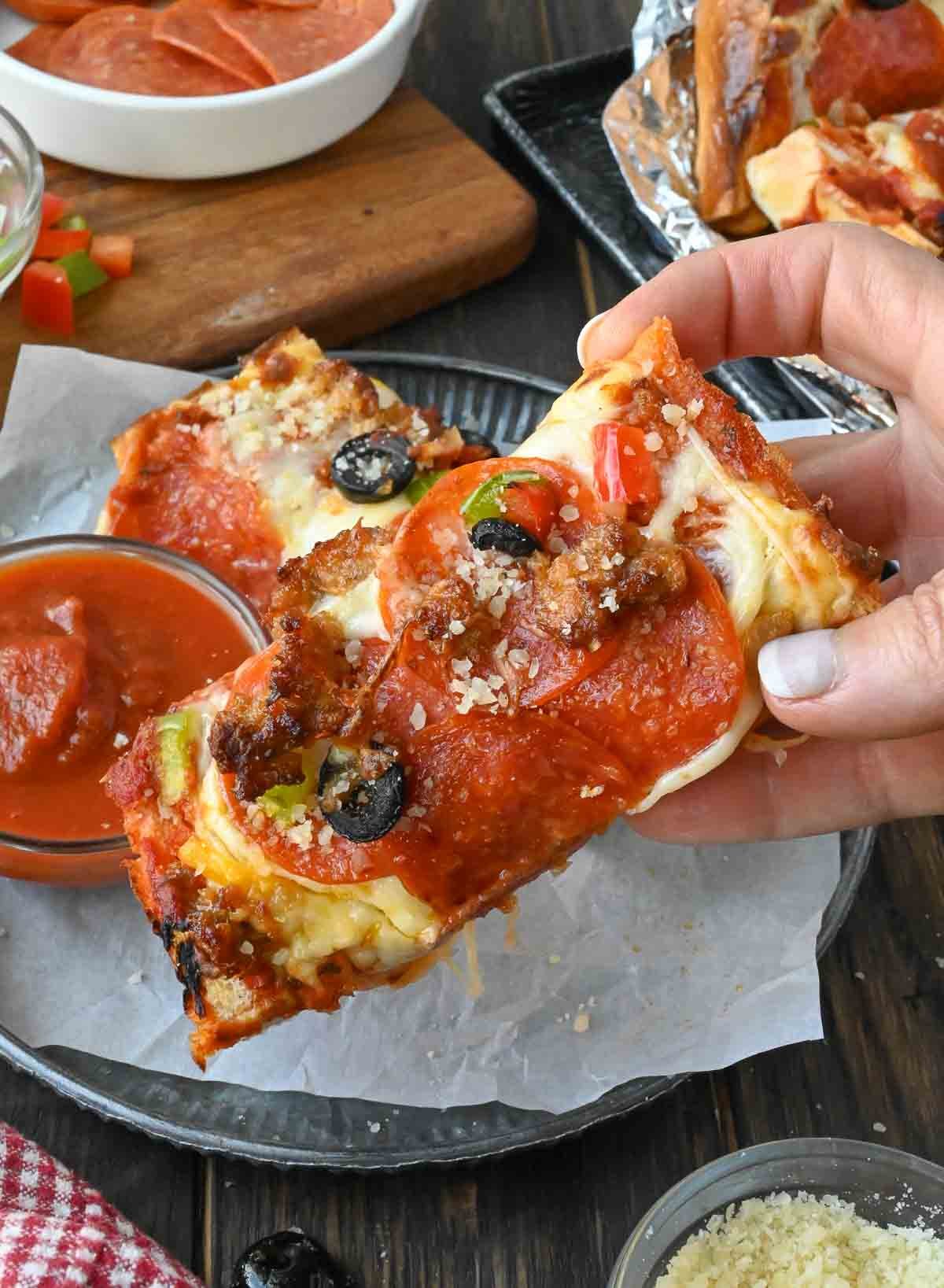 A slice of french bread pizza being picked up.