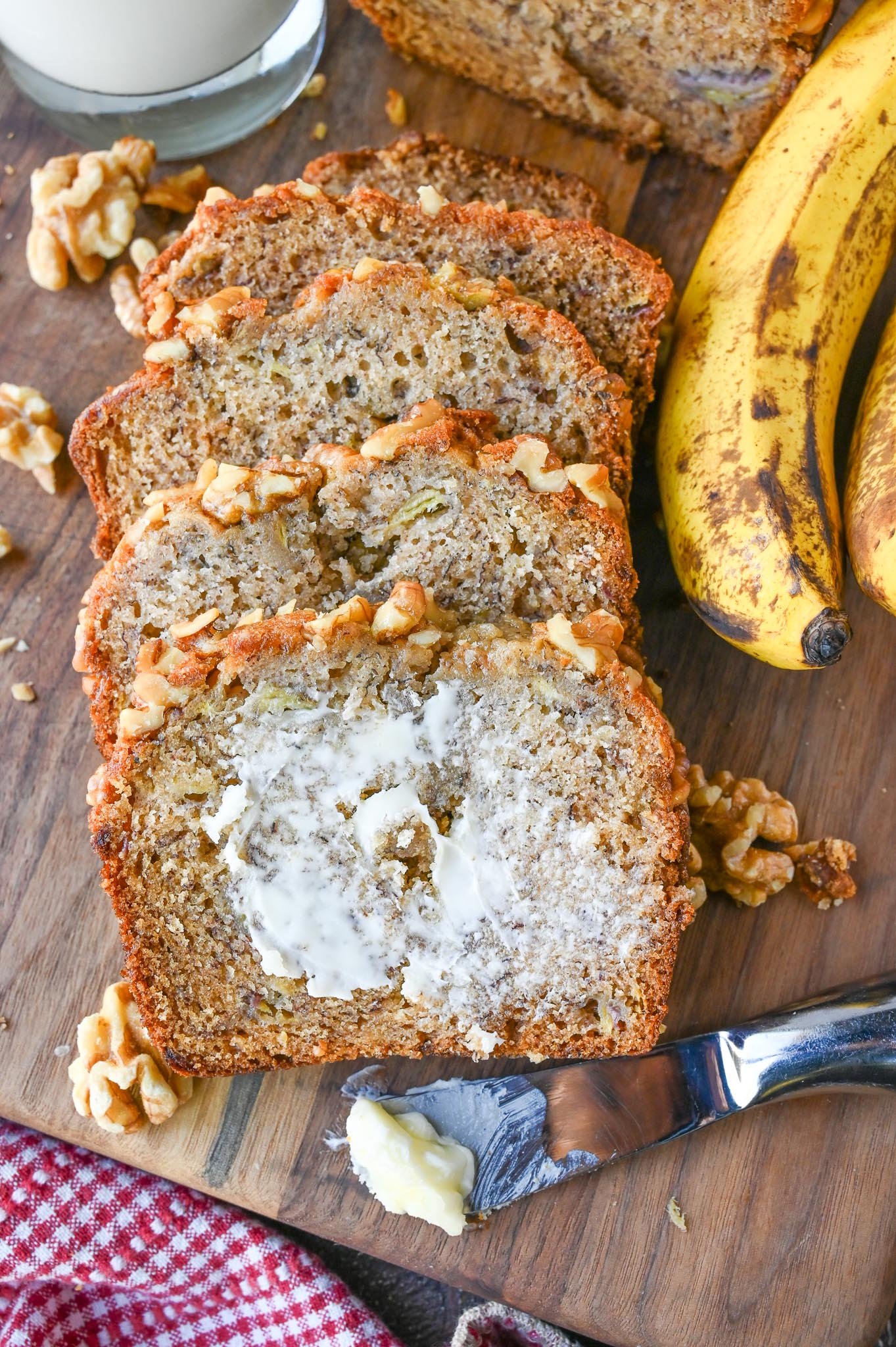 Slices of banana bread on a cutting board with butter on one slice.