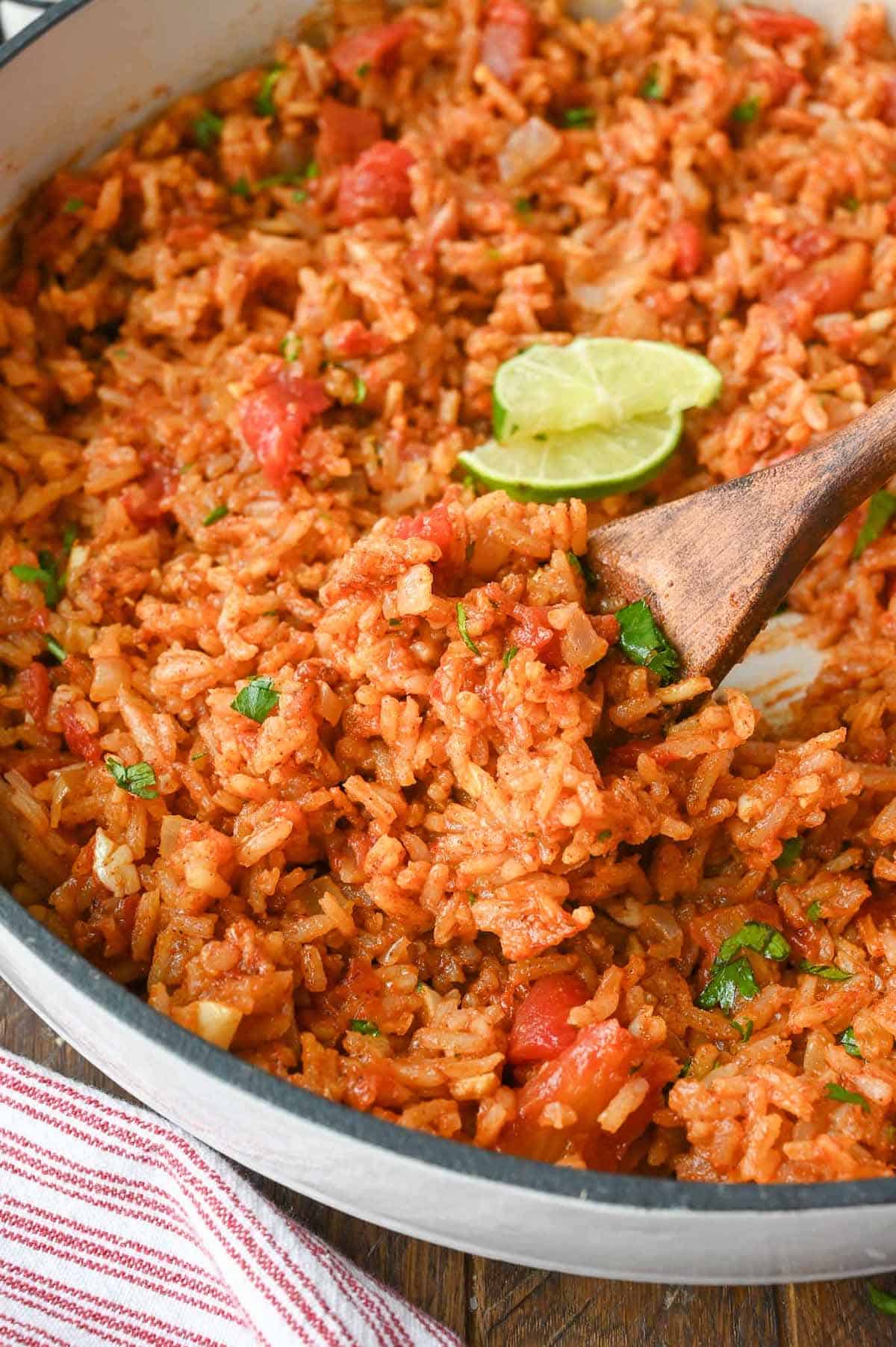 A wooden spoon scooping up some Mexican rice.