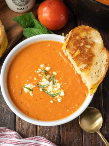 Tomato soup in a white bowl with grilled cheese.