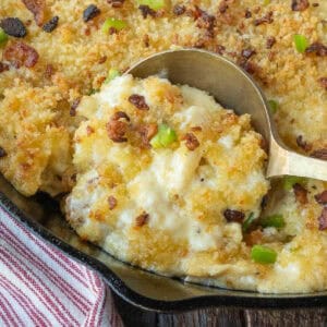 A spoon scooping up some mac and cheese from a skillet.