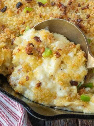 A spoon scooping up some mac and cheese from a skillet.