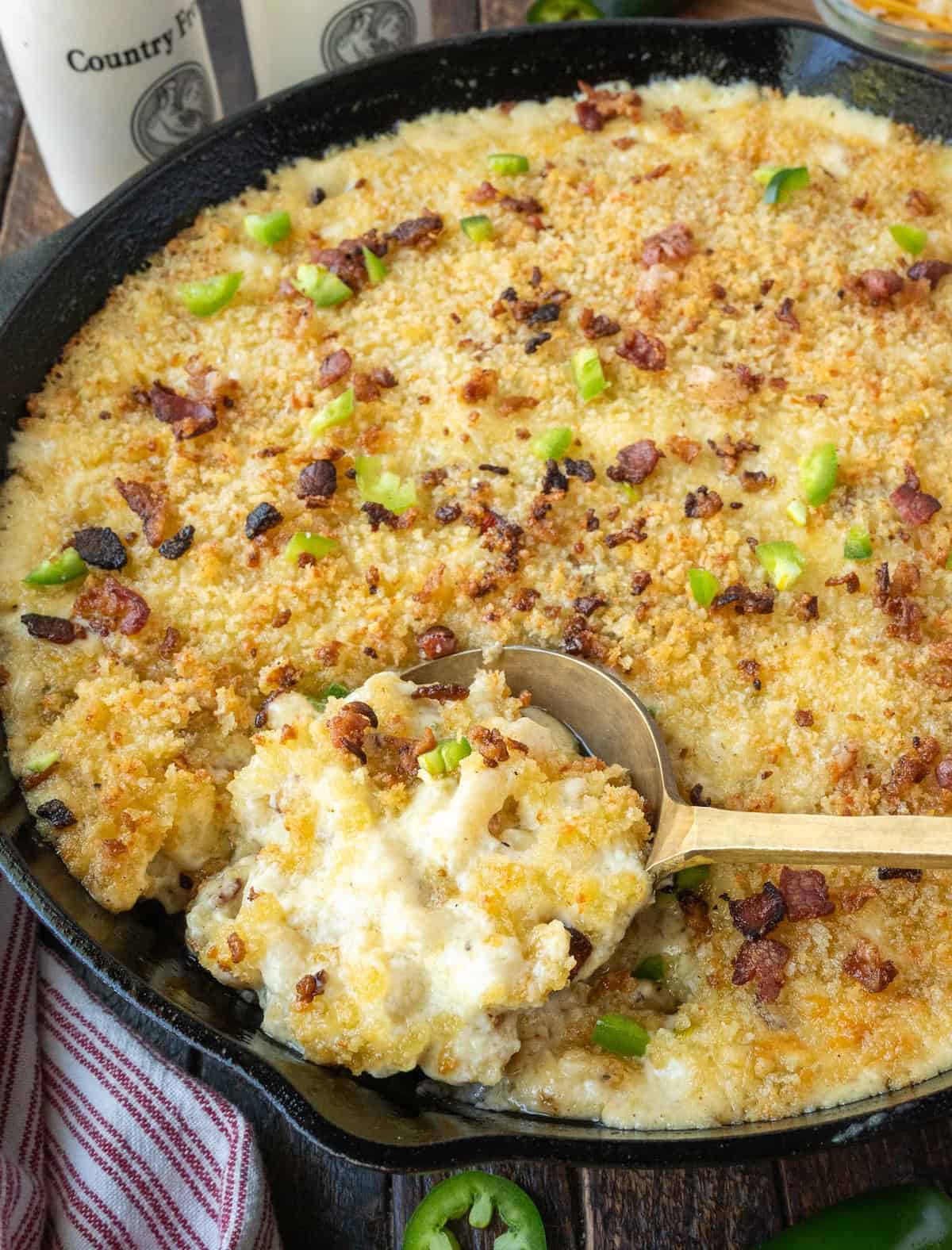 A spoon scooping out some mac and cheese from a skillet.