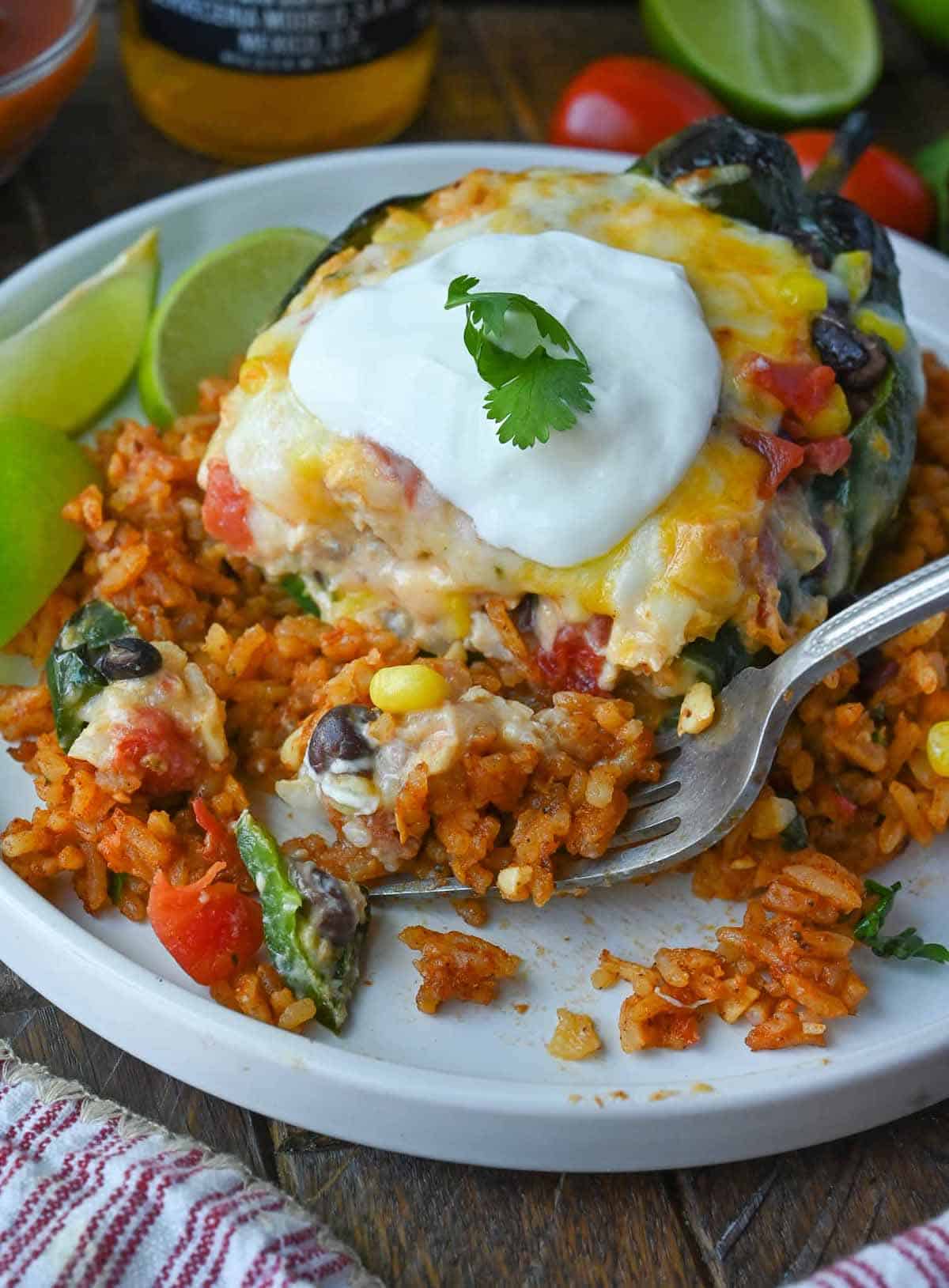 A fork scooping up a bite of a stuffed poblano pepper.