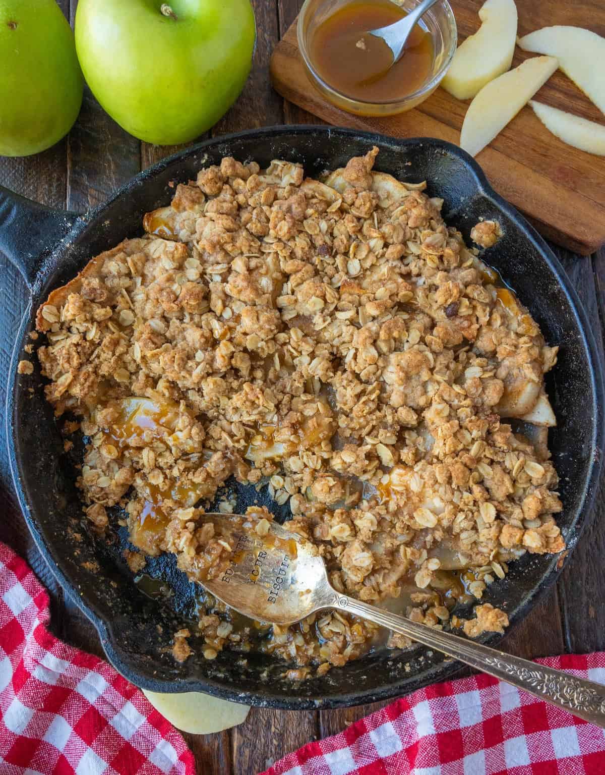 Apple crisp in a cast iron skillet with a spoon.