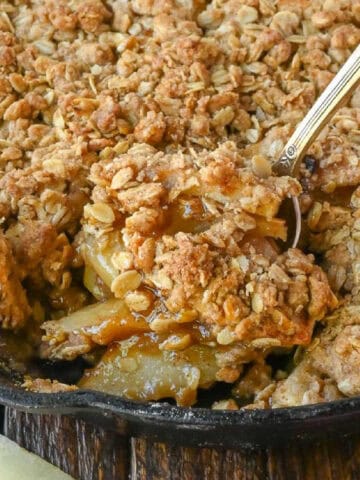 A serving spoon scooping up some apple crisp.