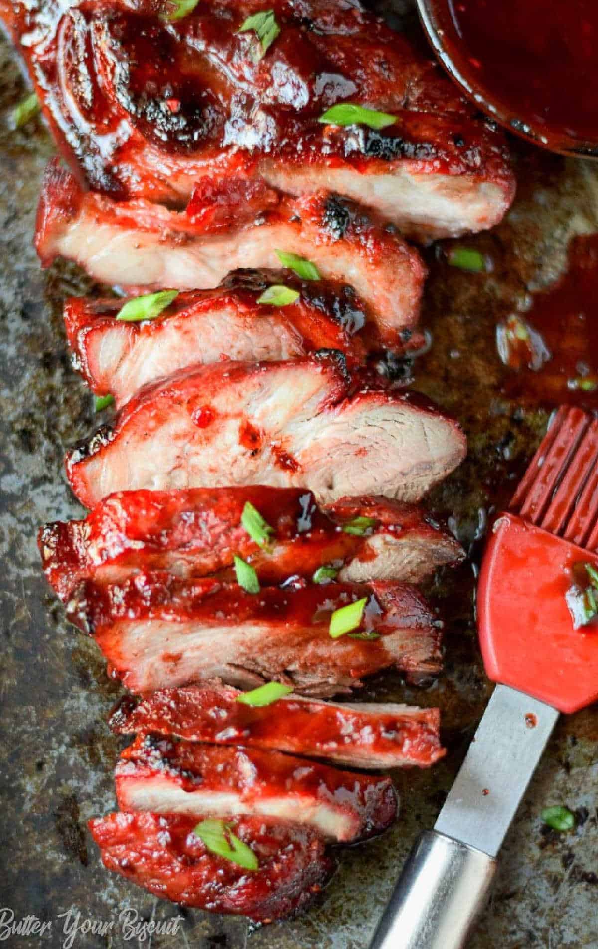 Sliced bbq pork with a red pastry brusg on the side.