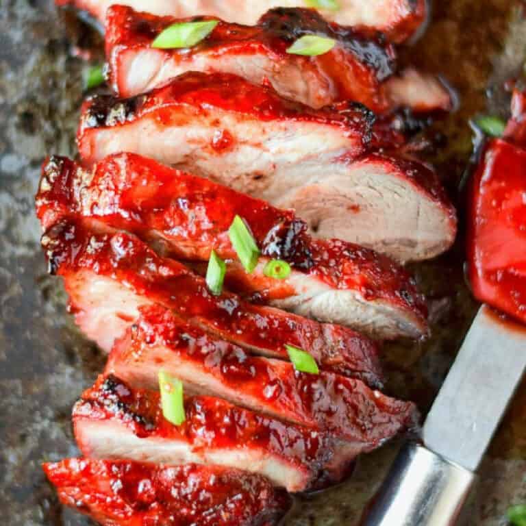 Sliced pork with a red pastry bruch on the side.