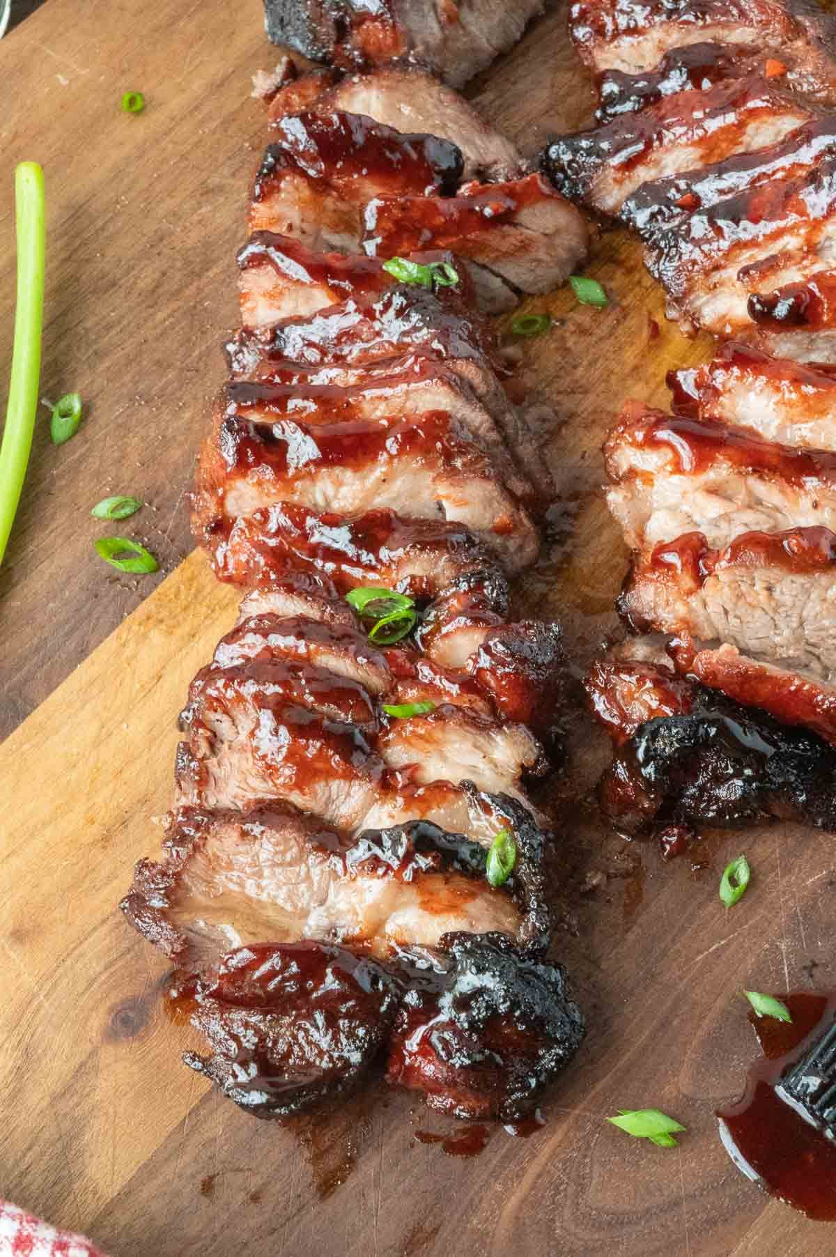 Chinese bbq pork on a cutting board cut into slices.