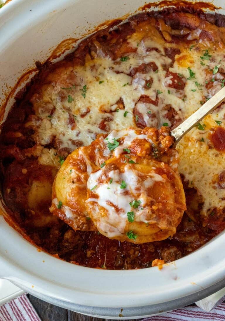 A serving spoon scooping up some slow cooker ravioli.