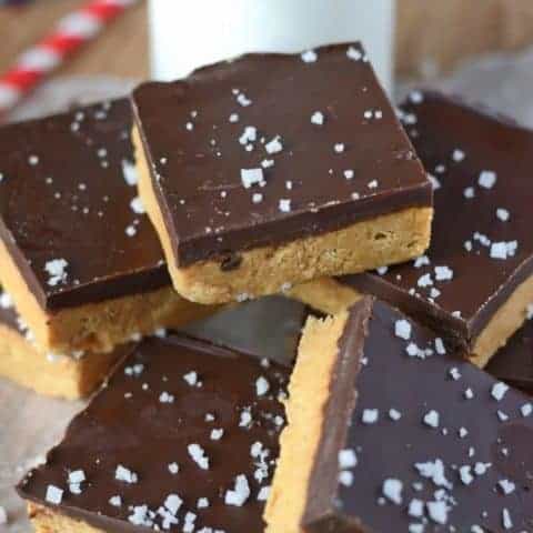 no bake peanut butter bars all piled up on top of each other with a glass of milk