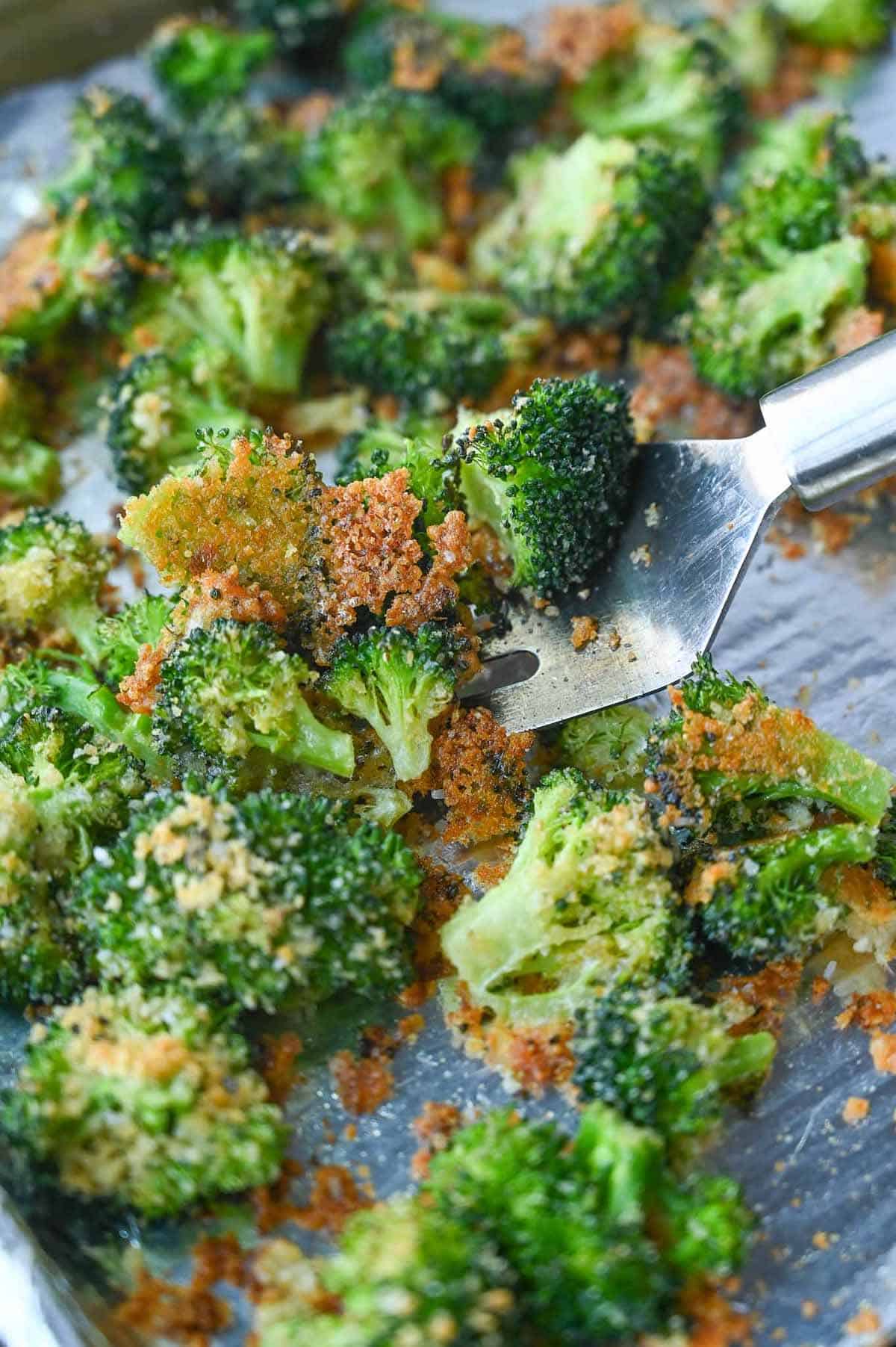 A spatula scooping up some roasted broccoli.