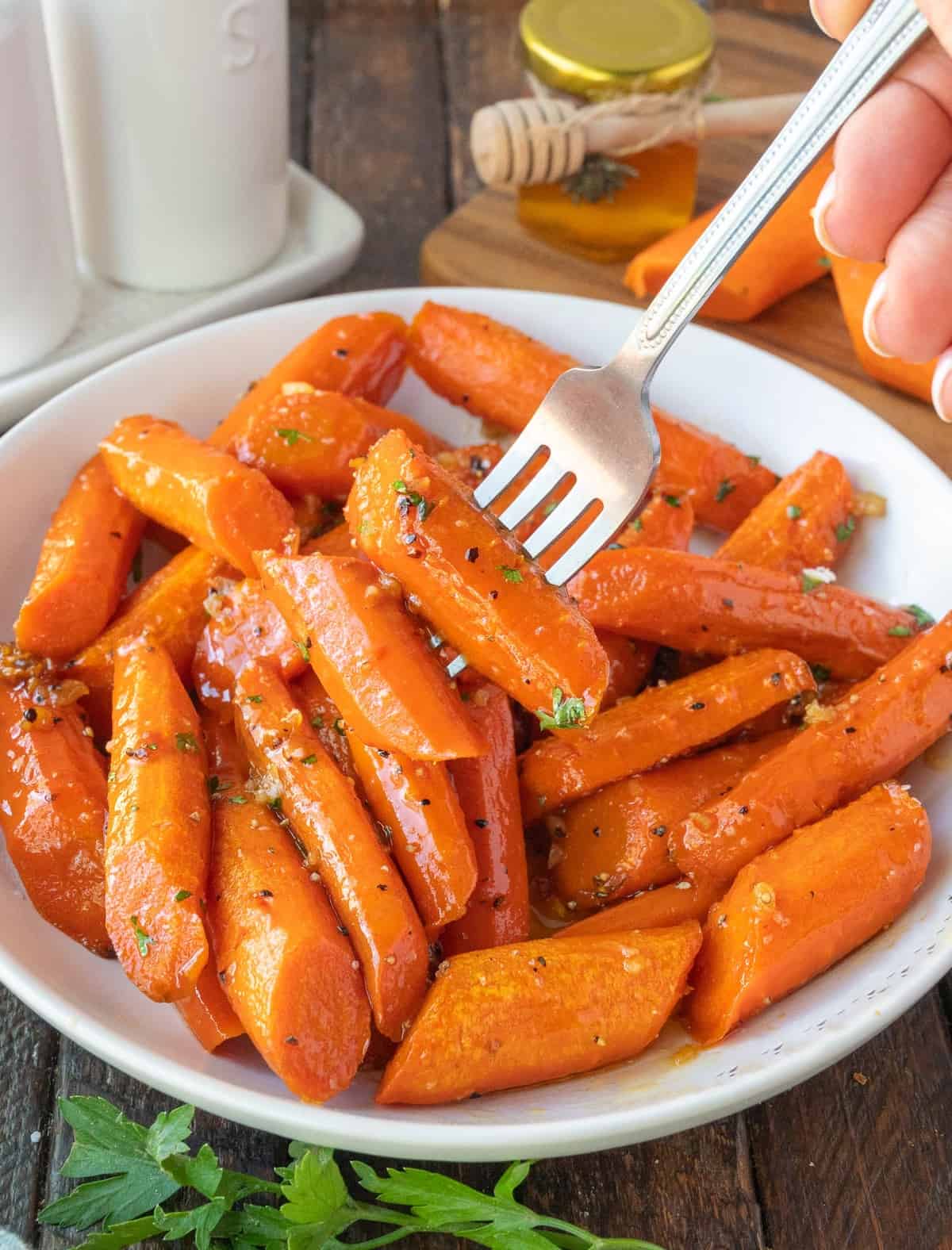 Roasted carrots in a serving dish with a fork picking up two.