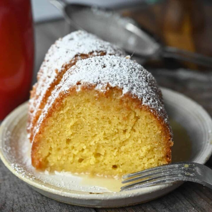 Two slices of rum cake on a plate with powdered sugar on top.