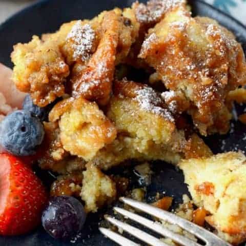 slow cooker french toast on a black plate with blueberries and strawberries