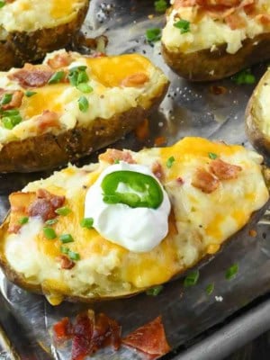 Bacon jalapeno twice baked potato on a baking sheet with sour cream on top.