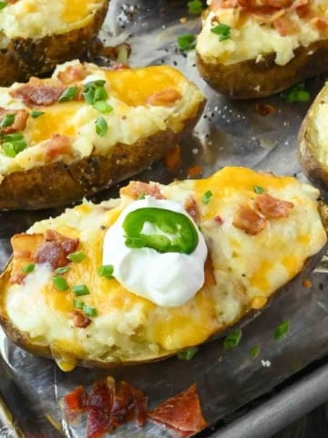 Bacon jalapeno twice baked potato on a baking sheet with sour cream on top.