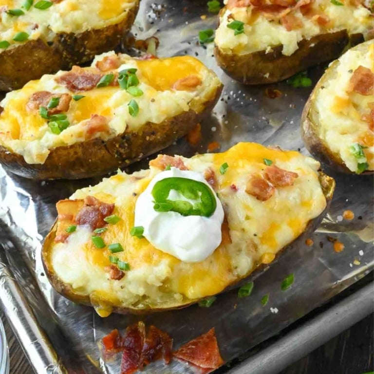 Bacon jalapeno twice baked potato on a baking sheet with sour cream on top.