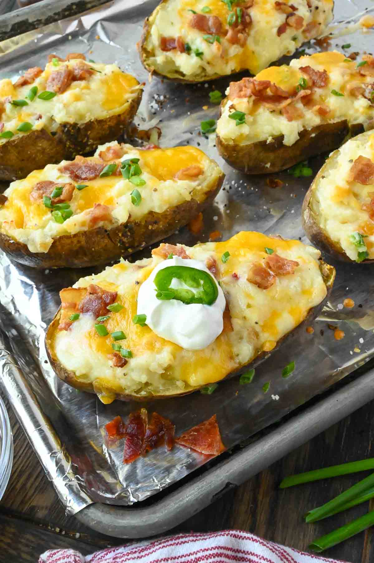 Bacon jalapeno twice baked potato on a baking sheet with sour cream on top.