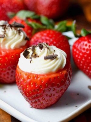 Cheesecake stuffed strawberries on a white plate.